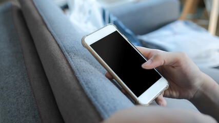 Cropped shot of woman hand is holding cell phone with white blank screen for input the text.