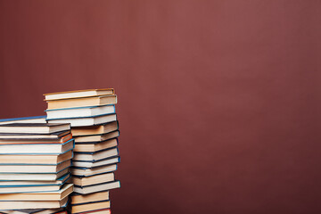 many stacks of educational books for exams in the library on the brown background of the university