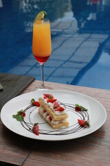 Strawberry Mille Feuille cake in white plate with fresh fruit punch.