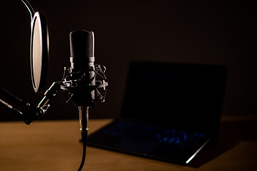 Close-up of a professional microphone on the background of a laptop in the dark