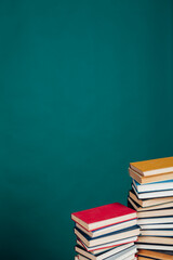 many stacks of educational books for exams in the library on the green background of the university
