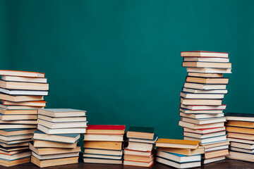 many stacks of educational books for exams in the library on the green background of the university