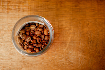 Roasted coffee beans in glass bottle on wooden background. Place for text. Banner concept.
