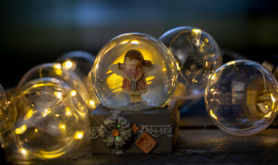 decorative snow globe with a girl angel on a dark wooden background close-up