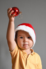 Happy little toddler boy holding christmas red ball. Happy New Year and Christmas holiday concept