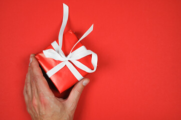 Red gift with a white ribbon in hand