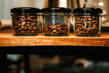 Roasted coffee beans in glass bottle on wooden table. Place for text. Banner concept.