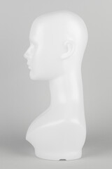 White mannequin head in profile on a gray background