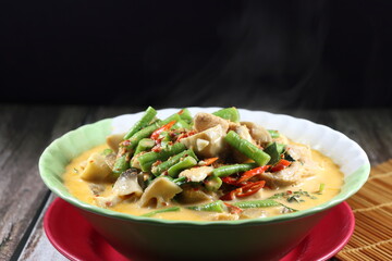 Spicy Thai curry soup of cutting fresh bean, mushroom and chicken seasoning with coconut milk and chilly paste in the bowl. Famous traditional menu in Asia restaurant. 