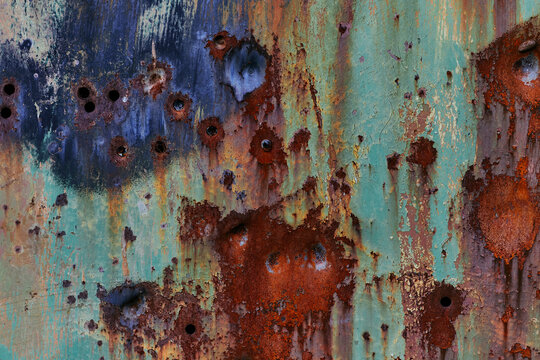 Texture of metal with dents and rust. Grunge metal with green paint and gunshot holes. Abstract rusty metal background for design and photoshop.