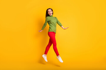 Fototapeta na wymiar Full size profile photo of funny lady jump up walking wear green pullover sneakers trousers isolated yellow color background