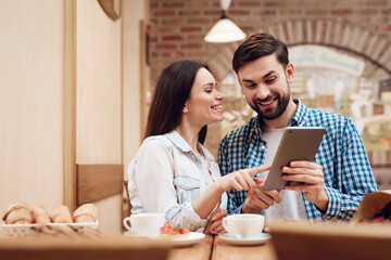 Young Couple Using Tablet in Modern Cafeteria.