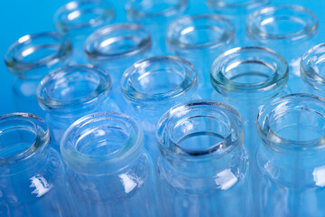 Dropping reagent on glass flask on blue background, closeup. Farmacy and medical concept background