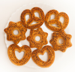 Curly Biscuits with poppy seeds on a white plate on a white background