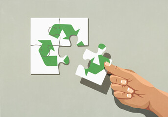 Hand finishing recycling symbol jigsaw puzzle with missing piece
