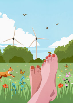 POV carefree barefoot woman relaxing in sunny, idyllic spring meadow with wind turbines
