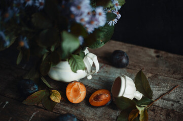 Cut plum near the old fashioned clay vase on wooden table