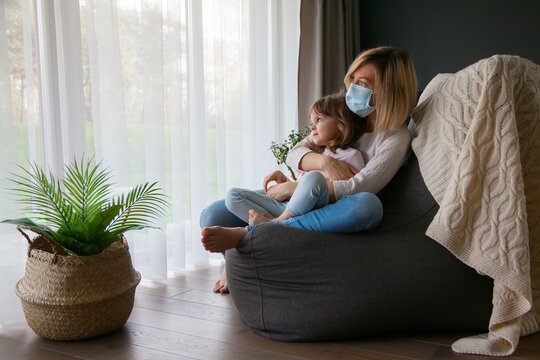 Mother in protective mask hugging her little daughter