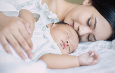 Fototapeta na wymiar Close up portrait of beautiful young asian or caucasian mother girl kissing her healthy newborn baby sleep in bed with copy space. Healthcare and medical love asia woman lifestyle mother's day concept