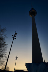 Silhouette des Fernsehturms mit Straßenlaternen am Berliner Alexanderplatz im Gegenlicht der...