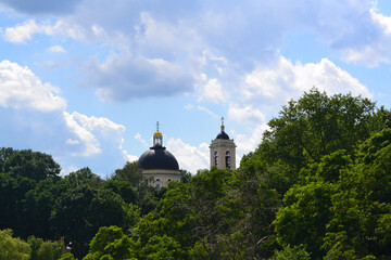 Fototapeta na wymiar Domes of Peter and Paul Cathedral towering over the treetops and beautiful blue cloudy sky on the background. Gomel, Belarus.