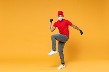 Fototapeta na wymiar Full length delivery employee african man in red cap t-shirt face mask gloves uniform work courier dealer service on quarantine coronavirus covid-19 virus concept isolated on yellow background studio.