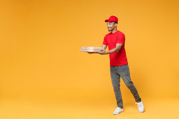 Full length delivery employee african man in red cap blank print t-shirt uniform work courier dealer service concept hold give food order pizza cardboard boxes isolated on yellow background studio