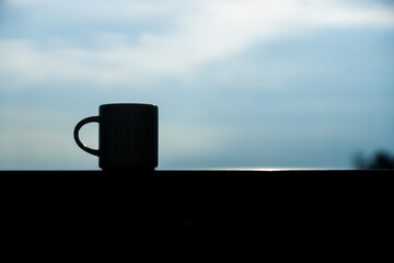 Close up silhouette coffee mug in the morning sky.
