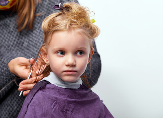 Hair cutting process. Beautiful little girl at the barber shop, hairdresser making a hair style to cute caucasian 4-5 year old little girl
