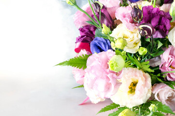 Summer wedding bouquet of multicolored roses close-up on gray and white background. Pink, yellow, lilac, white, purple roses and fern leaves in a bouquet. Dew drops on the flower petals