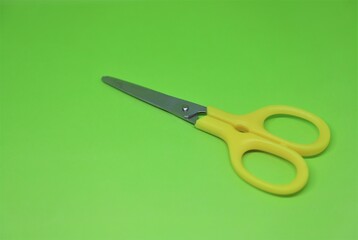 A yellow small child friendly stainless steel scissors isolated on lime green background with text space