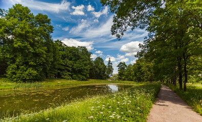 Summer landscape in a city Park with trees, grass, river, sky with clouds
