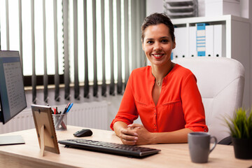 Executive freelancer finance entreprenerur wearing red blouse smiling at camera in workplace....