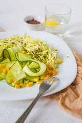 Selective focus photo of a salad of raw fresh vegetables, cabbage, cucumbers and corn, with the addition of flaxseeds, lemon and olive oil for menus, recipes, culinary publications