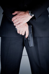 Detail photo of caucasian man in dark suit with a hand gun, bodyguard. - obrazy, fototapety, plakaty