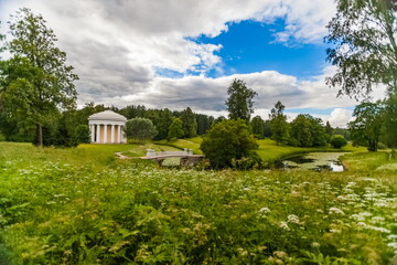 Summer landscape in the city Park with trees, pavilion, stone bridge over the river, sky with clouds