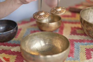 Woman playing on Tibetan singing bowl while sitting on yoga mat. Vintage tonned.
