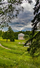 Fototapeta na wymiar Summer landscape in the city Park with trees, pavilion, stone bridge over the river, sky with clouds