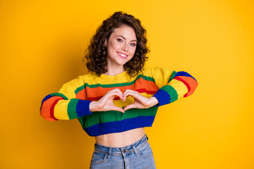 Photo of cute girl hands demonstrate heart shape toothy smile wear striped pullover isolated yellow color background