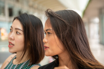 Naklejka premium Two beautiful young asian friends in a mall shopping center standing and talking