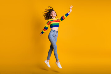 Fototapeta na wymiar Full length photo of sweet jumping lady wearing casual colorful sweater hand arm up isolated yellow color background