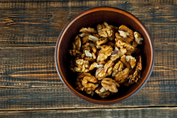 Peeled walnuts in a bowl. Nuts close up on an old wooden board. Food on a shabby table. Copy space and free space for text near food.