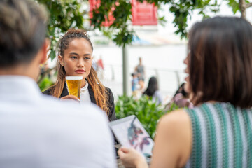 Business meeting outdoor. Two asian women and one asian man seated at a restaturant table