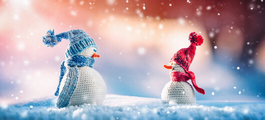 Little knitted snowmen on soft snow on blue background