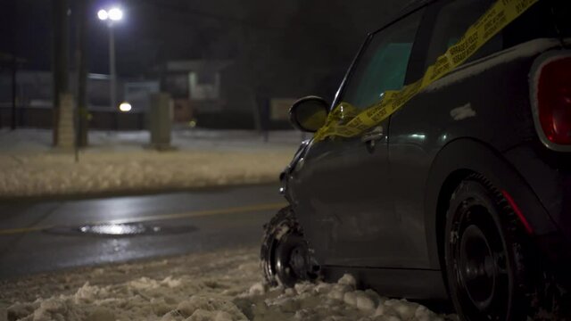 Aftermath of motor vehicle accident car accident on winter night in snow with small vehicle wrapped in caution tape