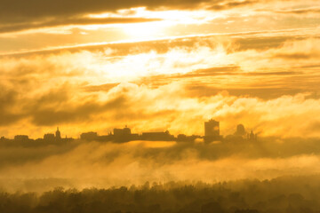 Sunset in city with fog, mist and orange sunset clouds