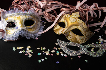 Venetian masks and carnival props from Brazil arranged on black surface, selective focus.