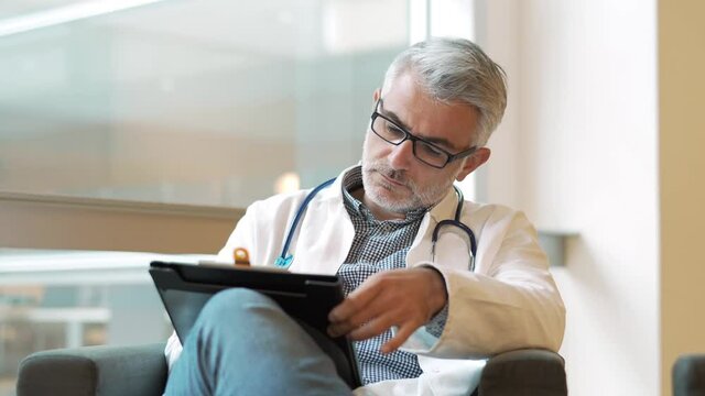 Portrait of doctor in hospital office working laptop