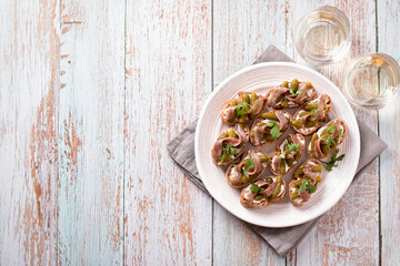 Anchovies toasts and two glasses of white wine on worn wooden table top, horizontal image