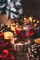 Mulled wine on table with Christmas lights and red napkin, cozy winter still life. Winter lifestyle at home, winter drink closeup, warm atmosphere